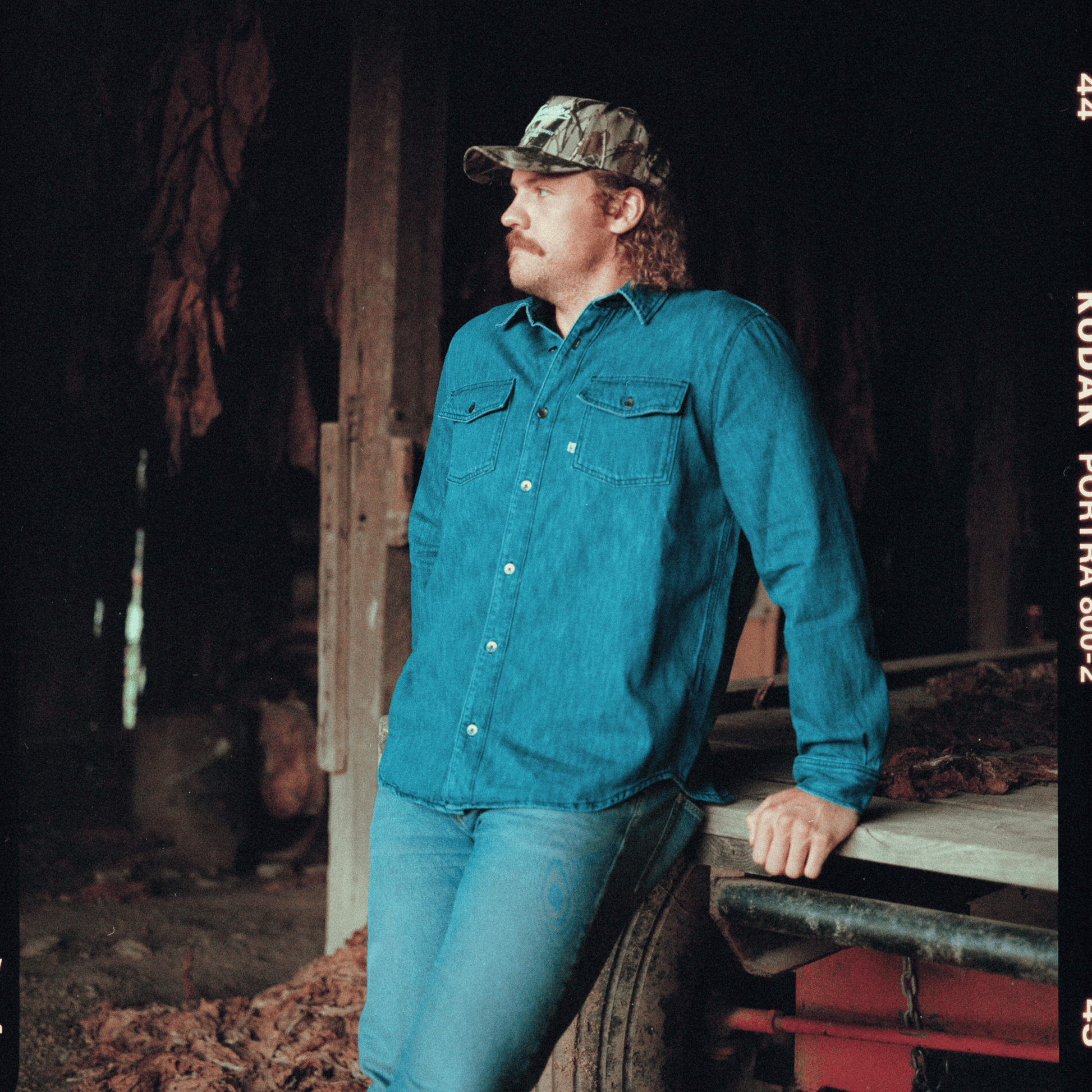 Man wearing a blue shirt and cap standing in a rustic setting