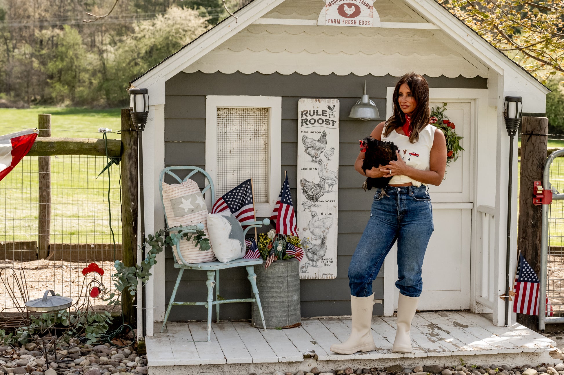 Woman holding chicken standing outside farmhouse