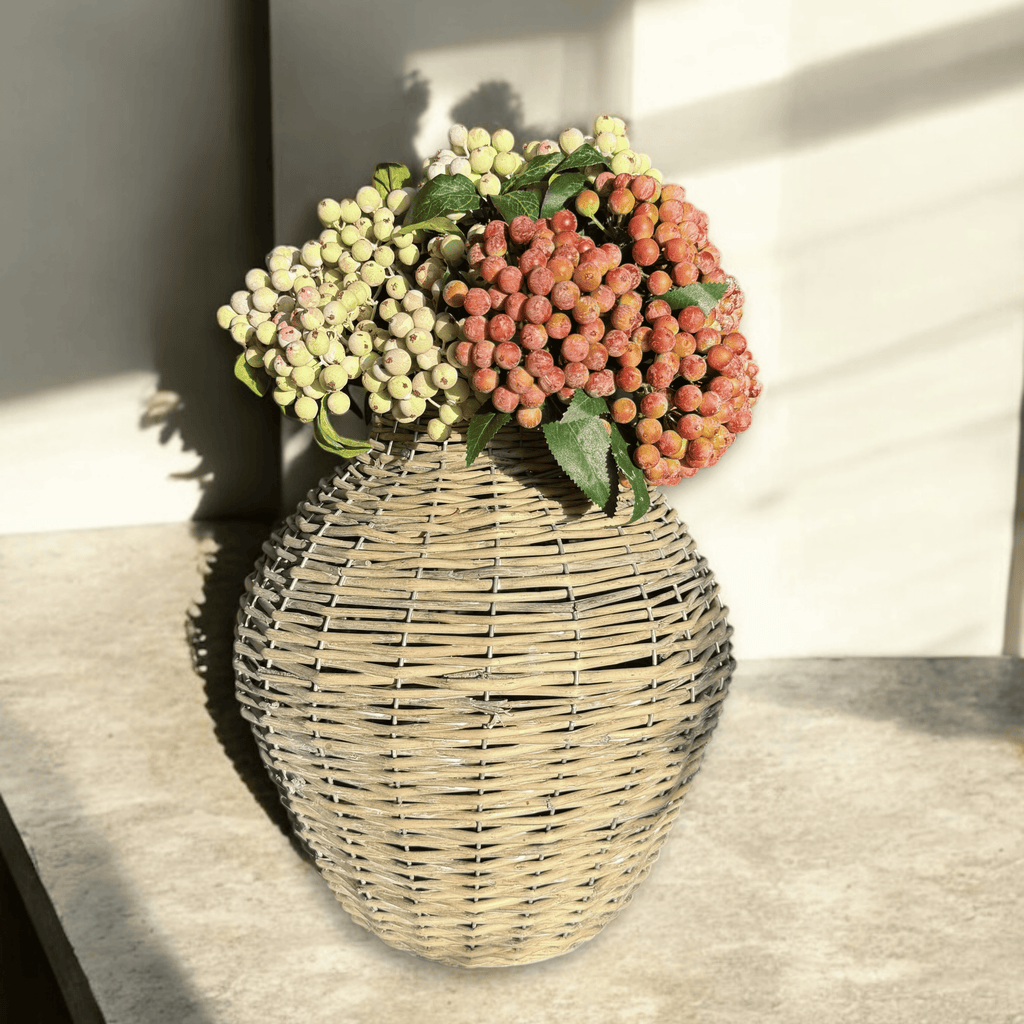 Wicker vase with flowers on a light surface